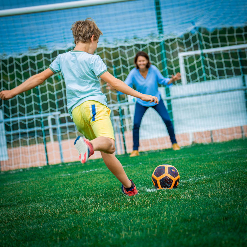 Enfant qui joue au foot avec une femme